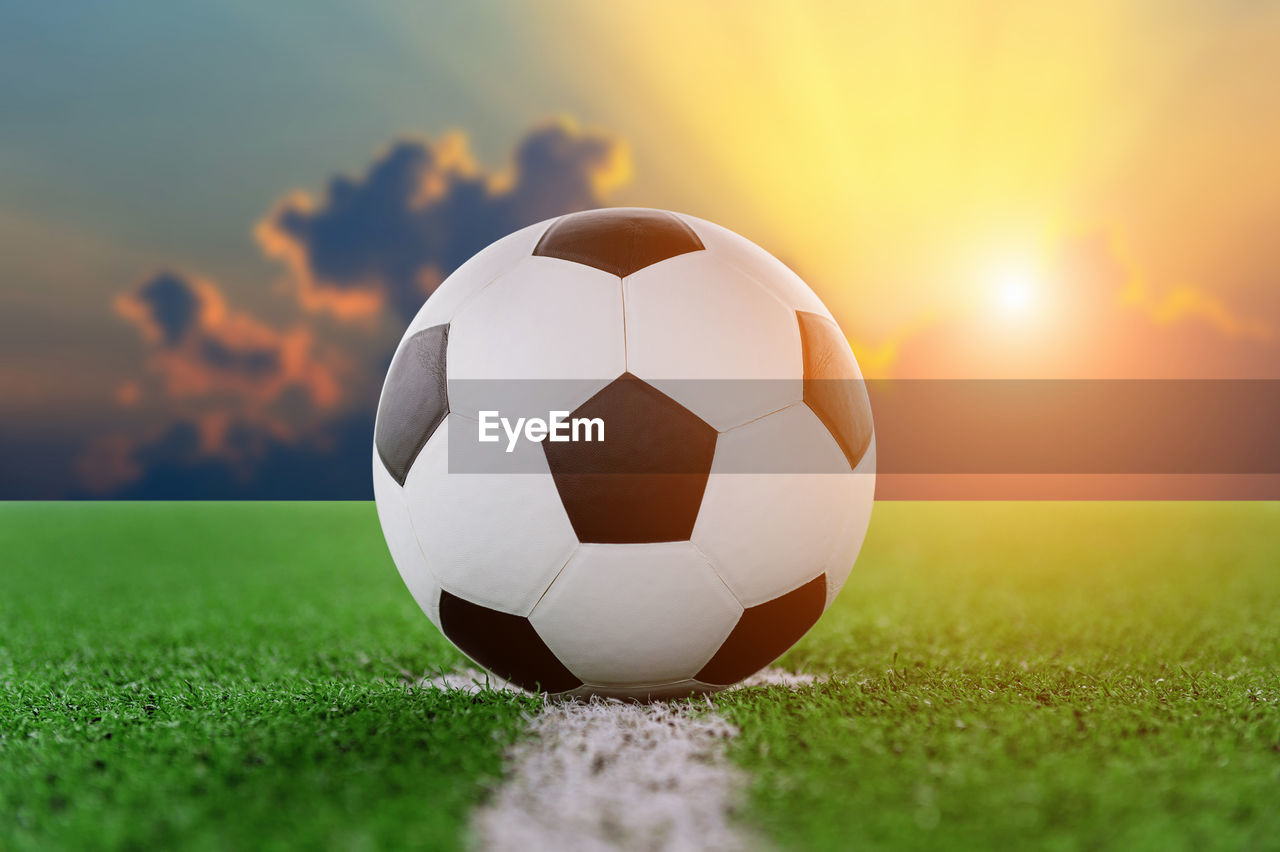 Digital composite of soccer ball on playing field against sky 