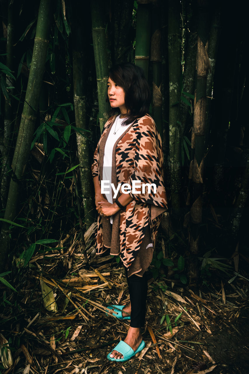 full length of young woman standing in forest