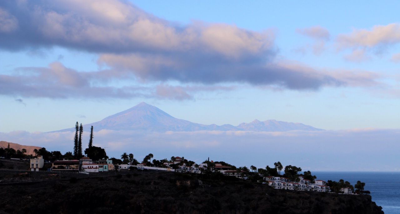 Scenic view of town on cliff with mountains against sky at tenerife