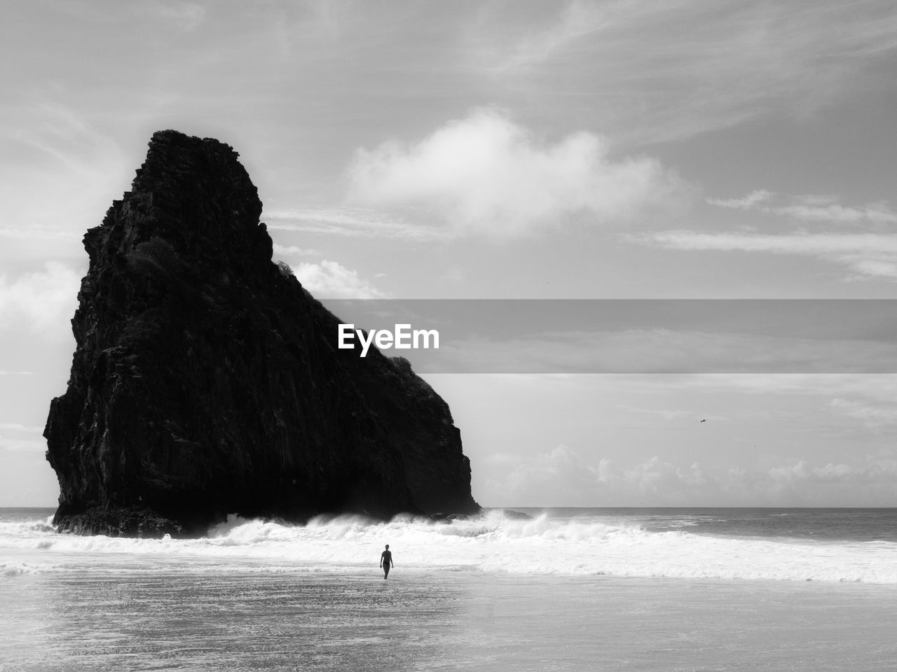 Silhouette person on shore at beach against sky