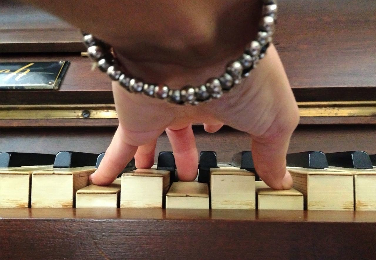 Close-up of cropped hand playing piano