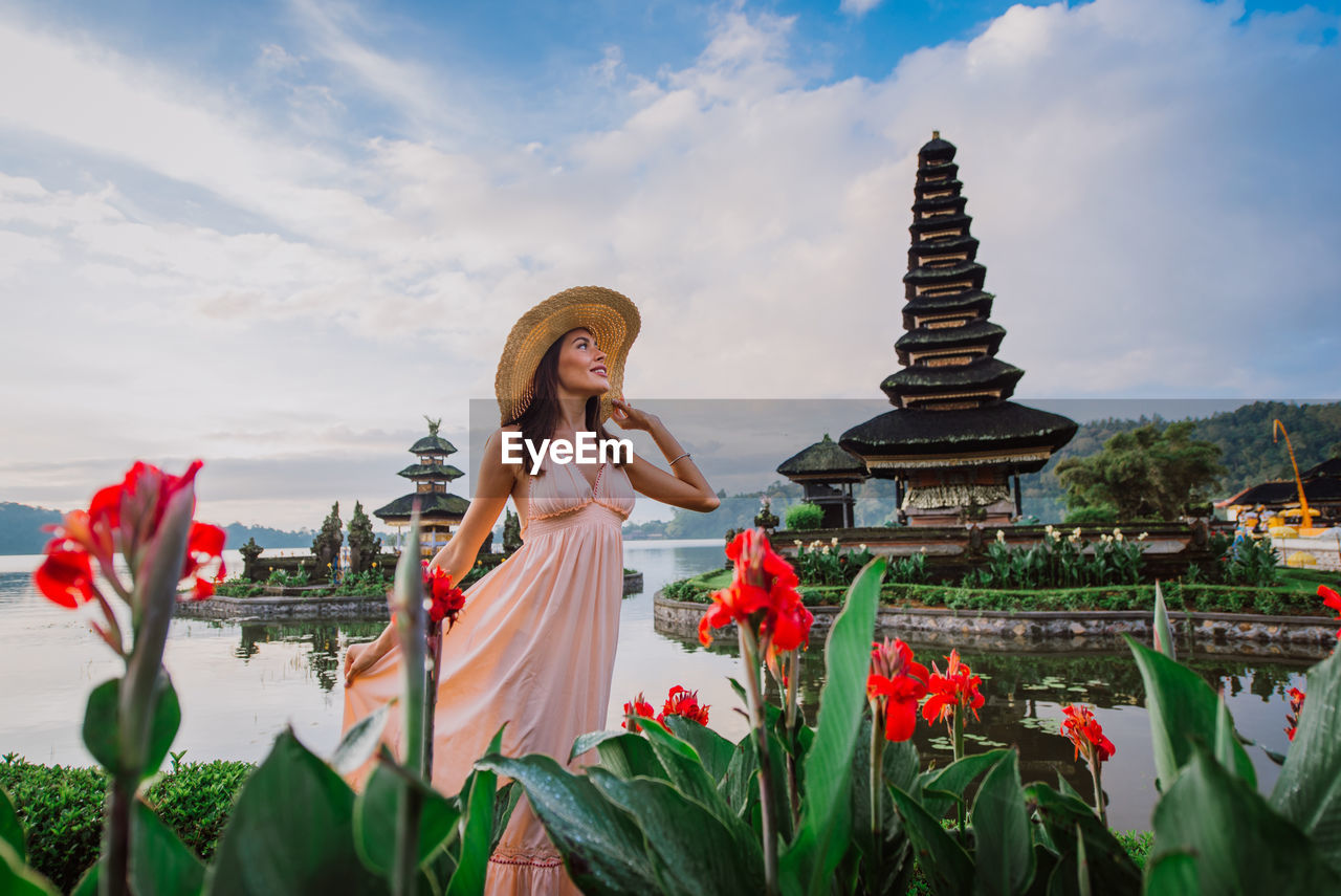 Woman standing at pura ulu danau temple against sky during sunrise