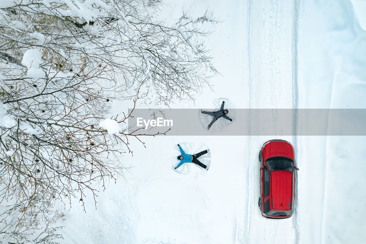 Couple making snow angels in winter landscape