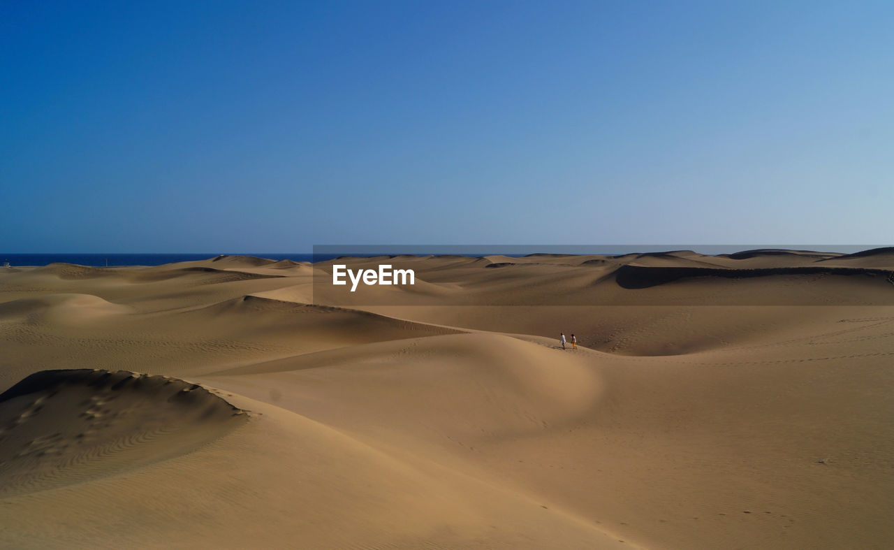 Scenic view of desert against clear blue sky