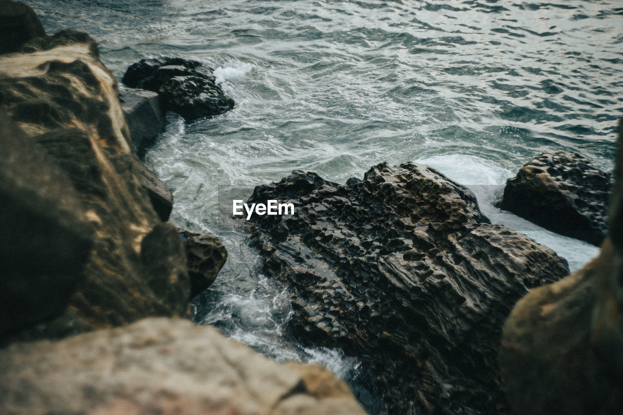 HIGH ANGLE VIEW OF ROCKS ON SEA