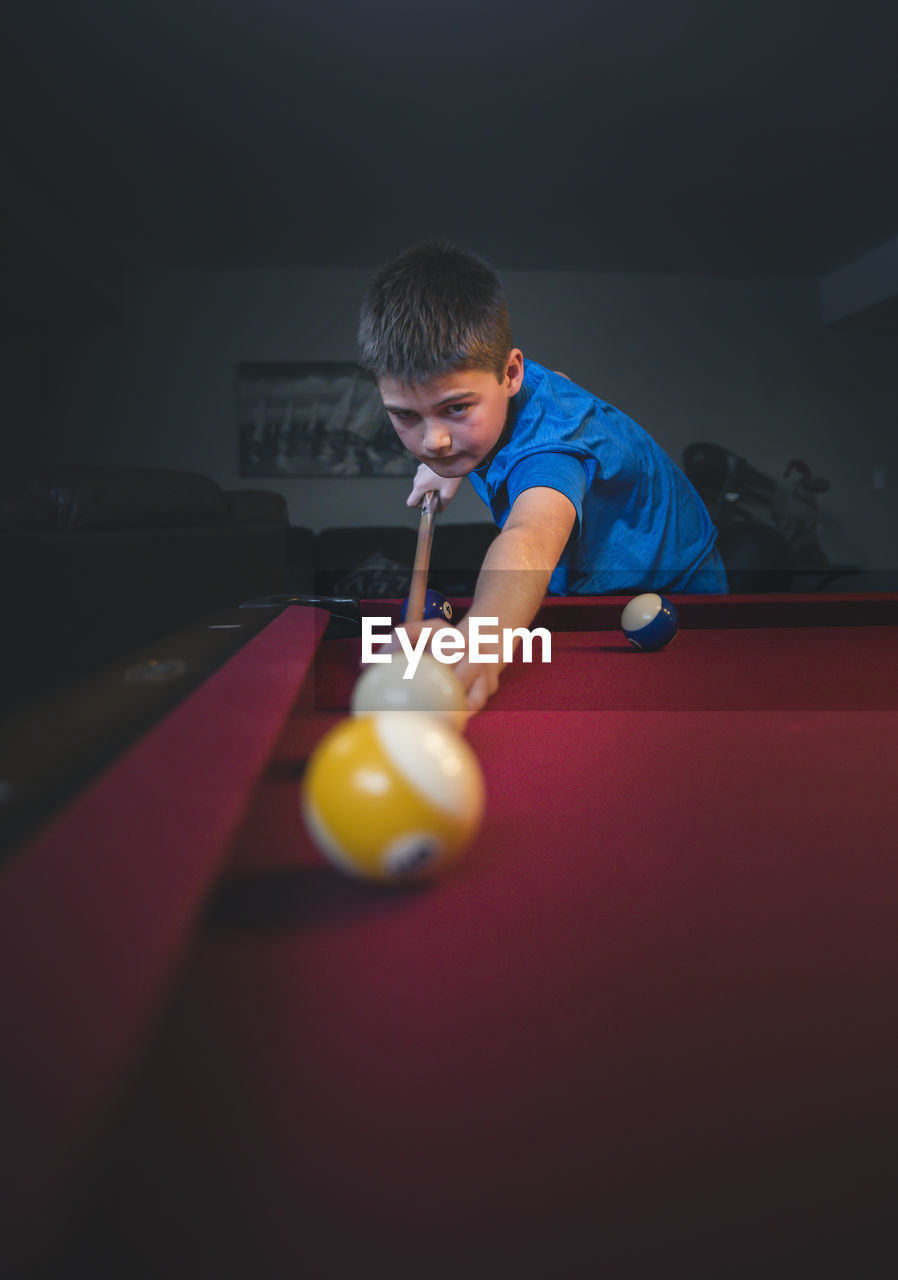 Boy aiming cue ball while playing pool