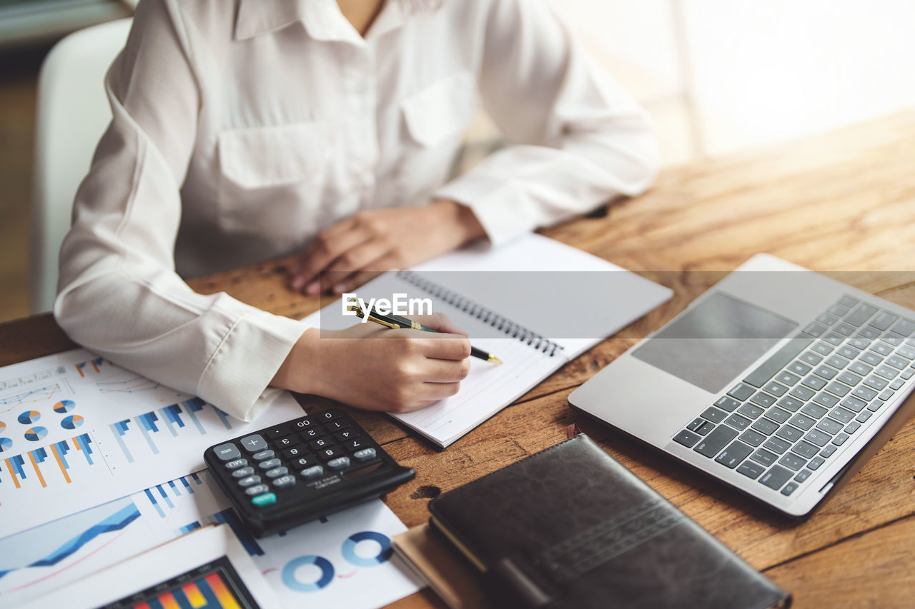 Midsection of business person working at desk in office