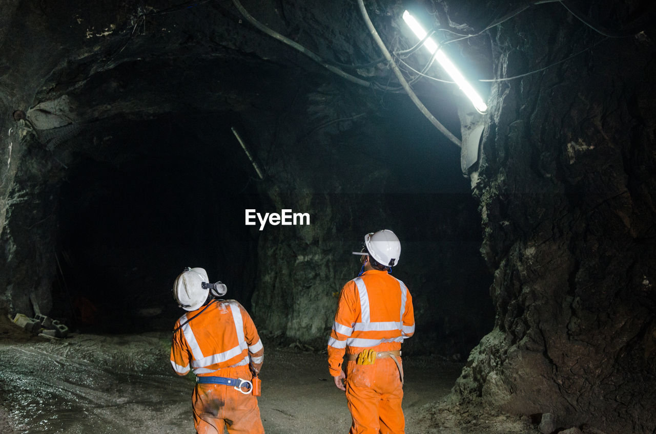 Rear view of people working in cave