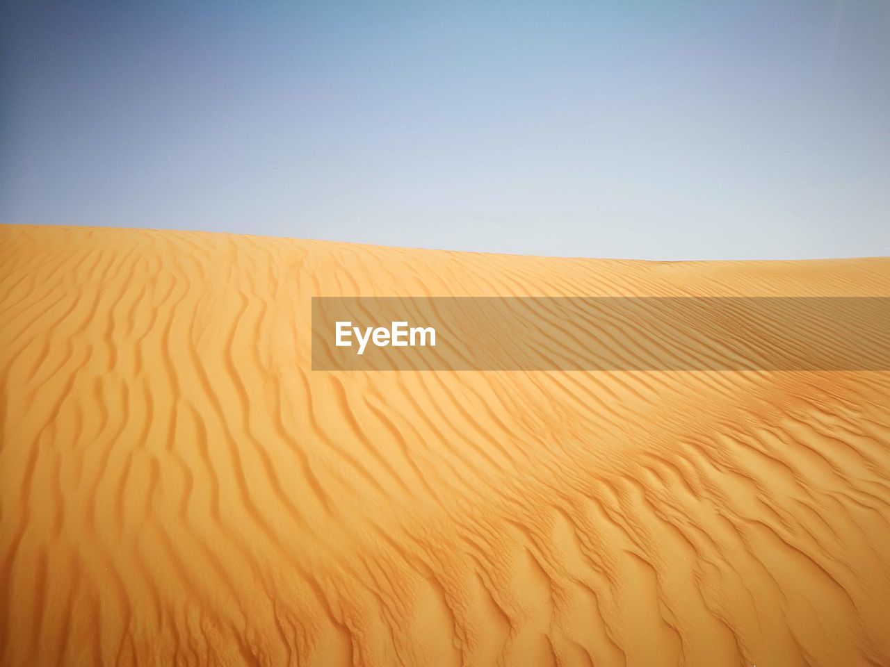 Sand dunes in desert against clear sky