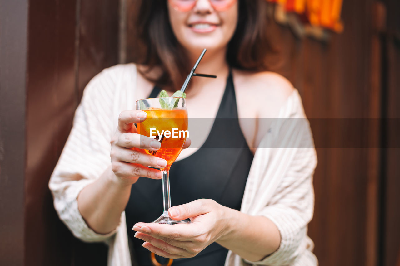 Stylish happy young woman forty years plus size body positive with glass of cocktail