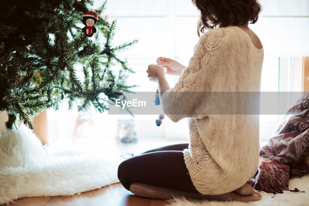 REAR VIEW OF WOMAN WITH CHRISTMAS TREE