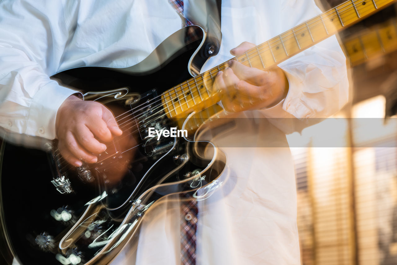 Midsection of man playing guitar