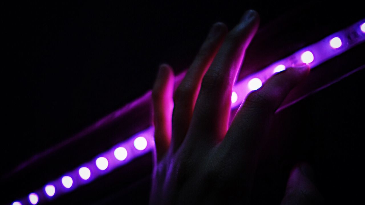 Cropped hand by illuminated lighting equipment