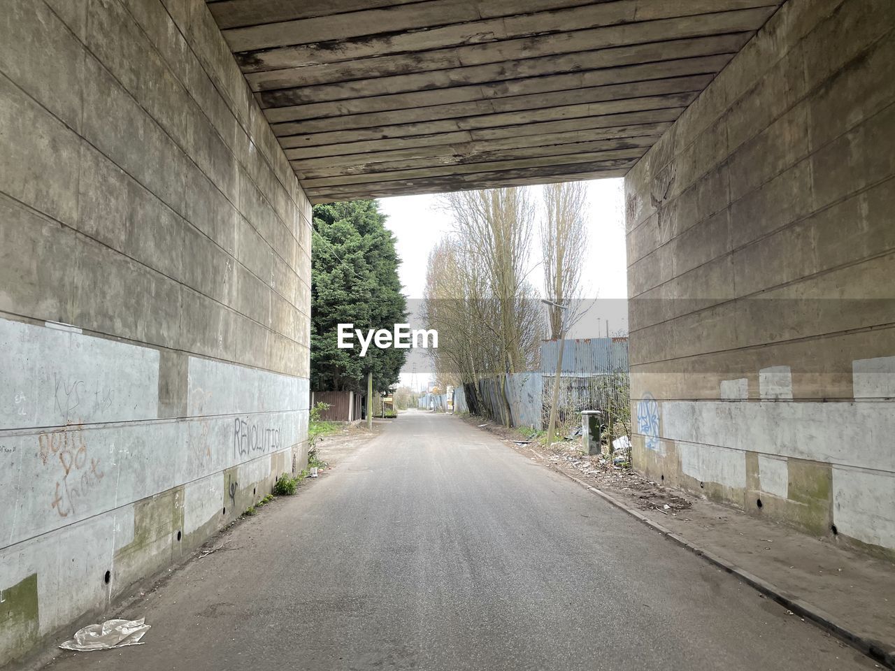 EMPTY ROAD ALONG WALLS AND TREES