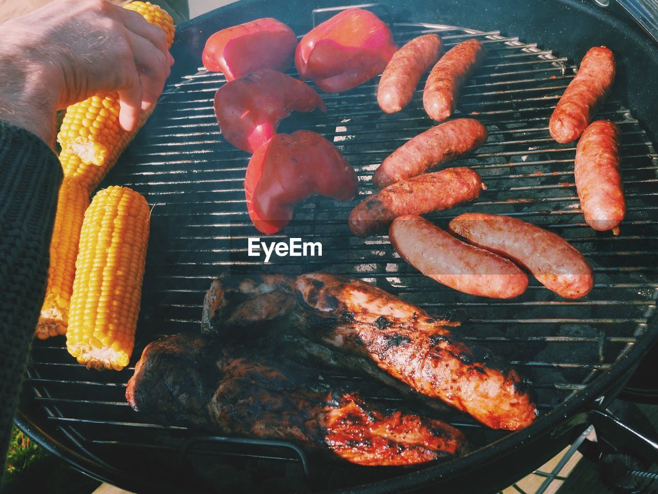Cropped hand grilling food on barbecue