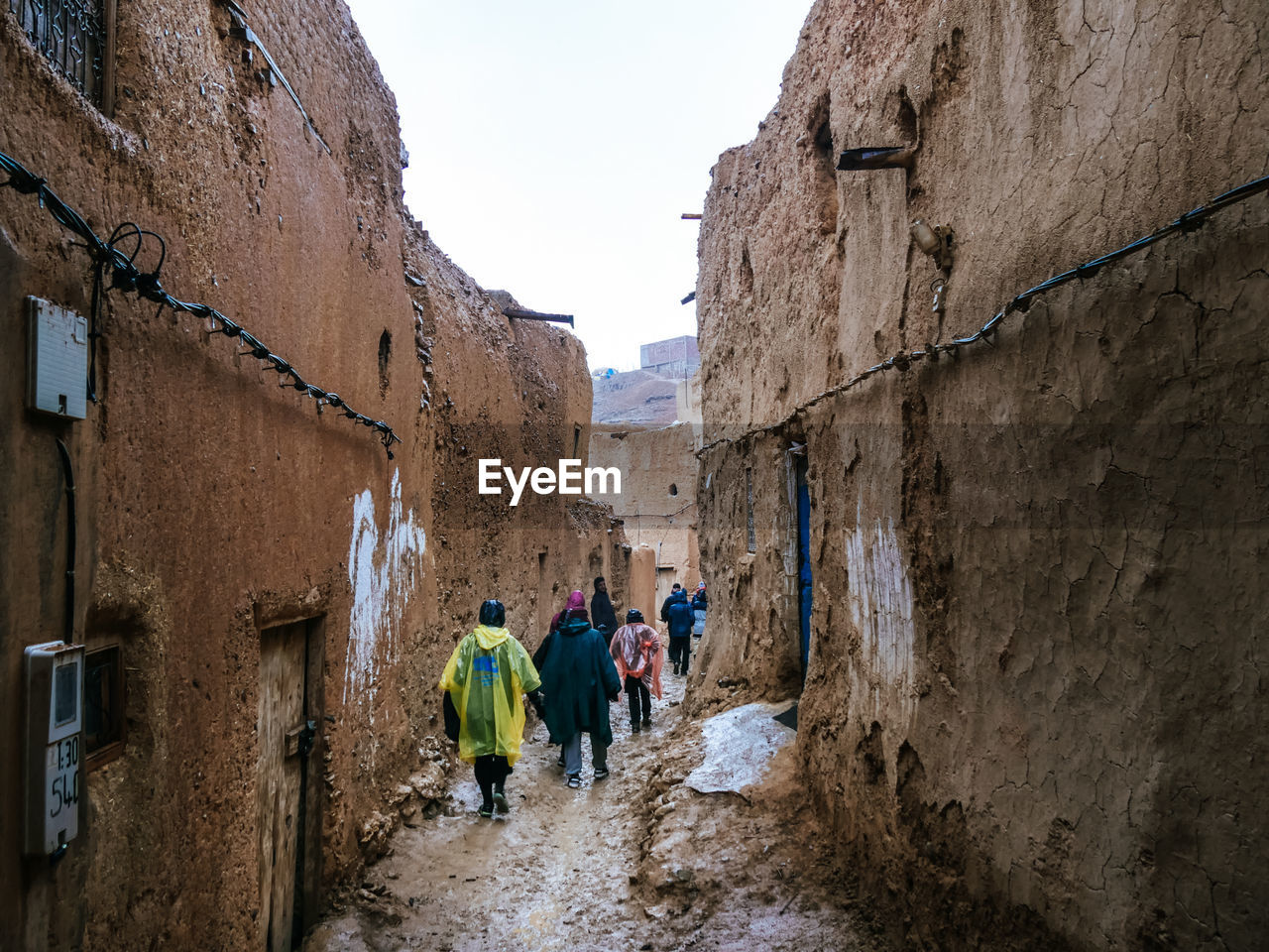 REAR VIEW OF PEOPLE WALKING ON ALLEY