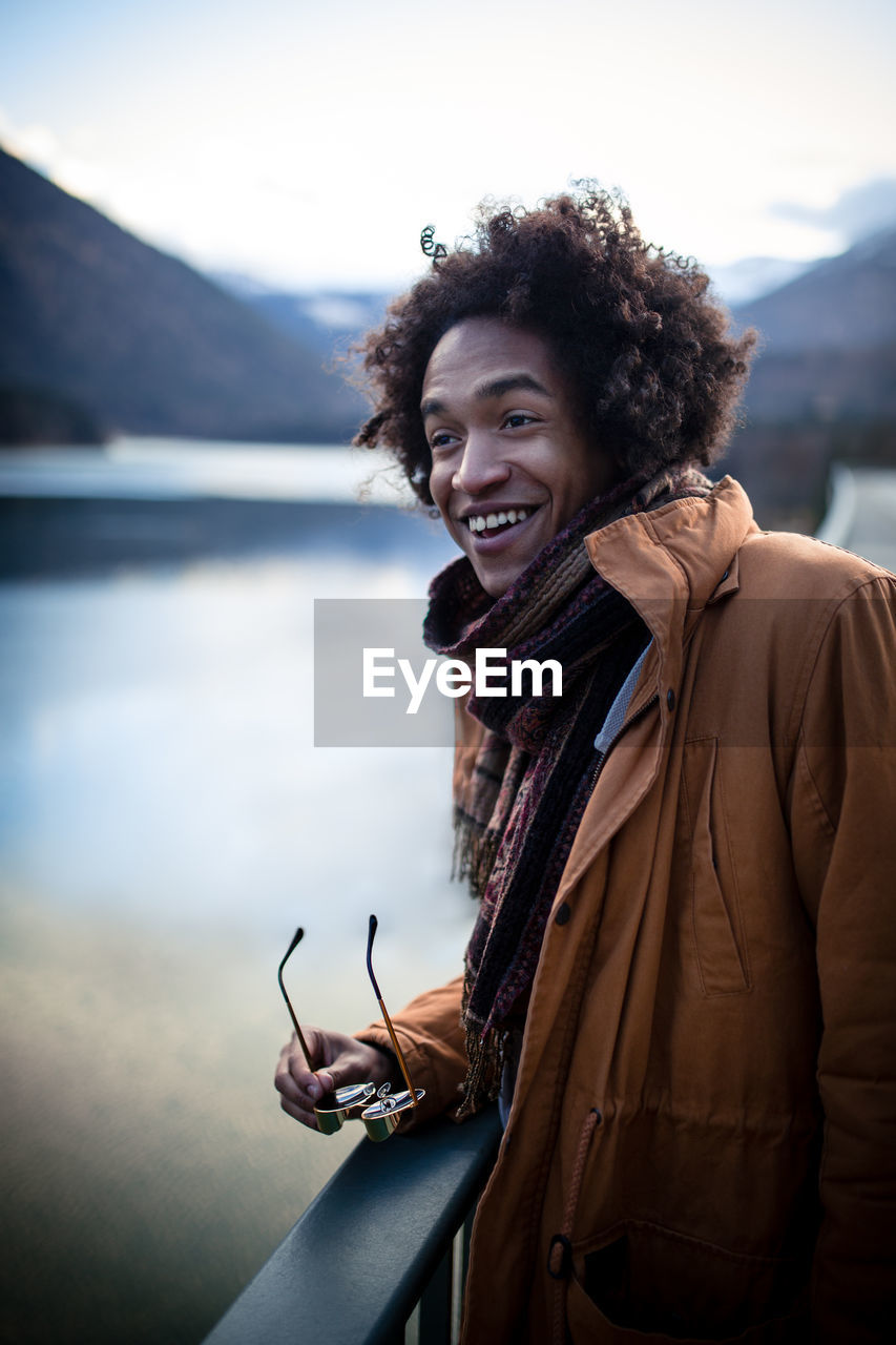 Smiling man standing against river