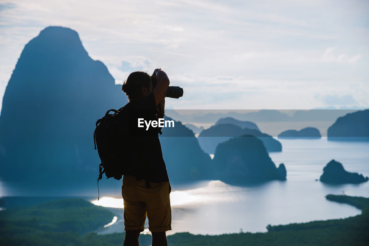 MAN PHOTOGRAPHING AGAINST SKY