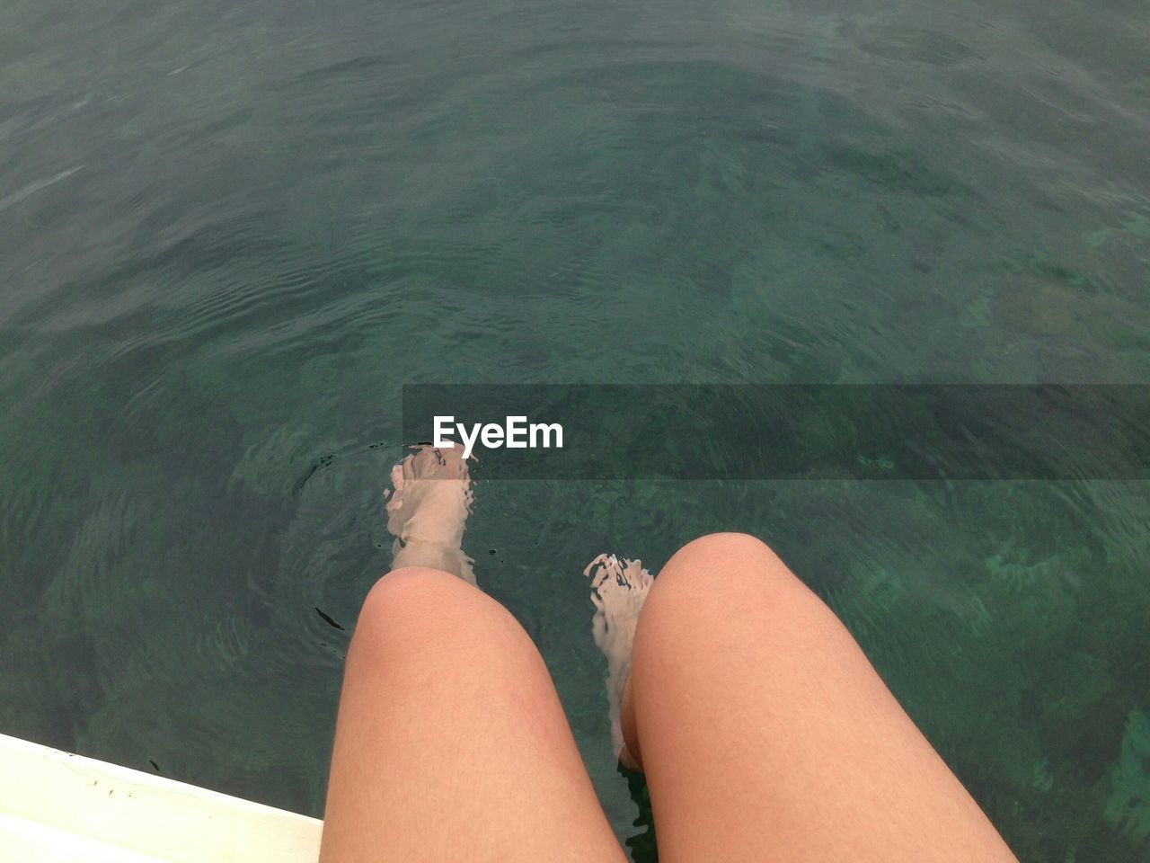 LOW SECTION OF WOMAN SITTING BY WATER