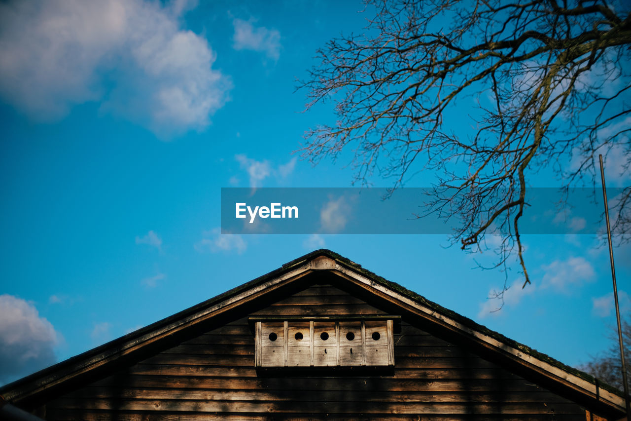 Roof of wooden house with birdhouses against blue sky