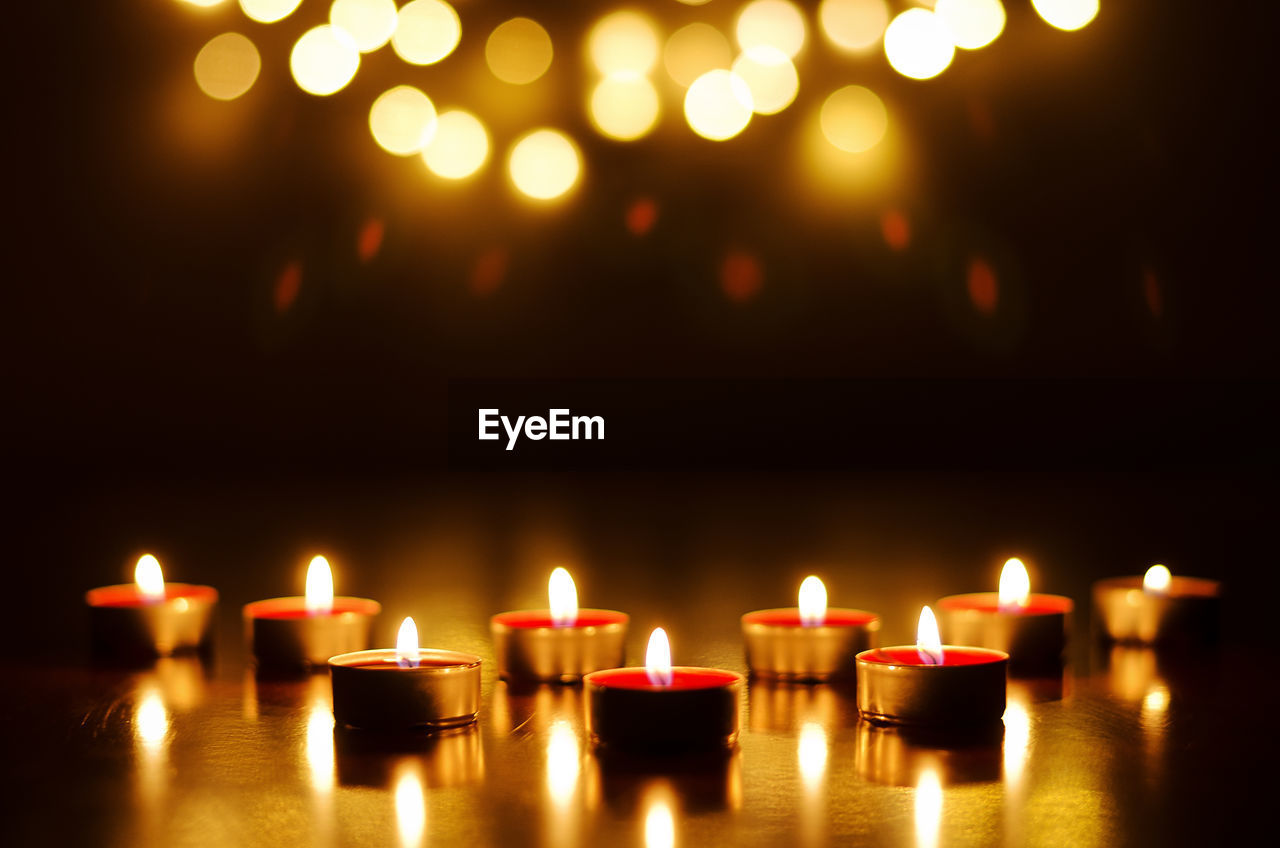 Burning candles with festive bokeh on black background. holiday concept, prayer and hope.