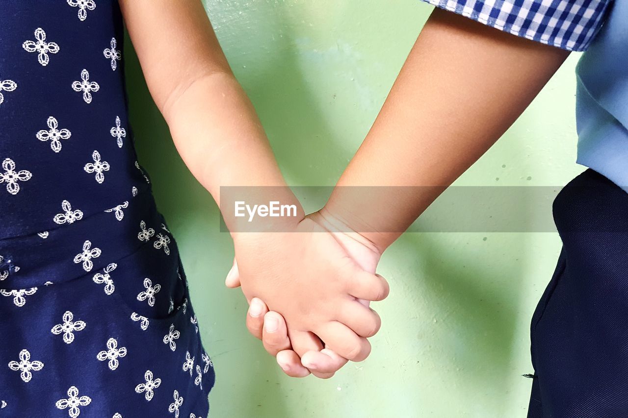 Cropped image of boy and girl holding hands