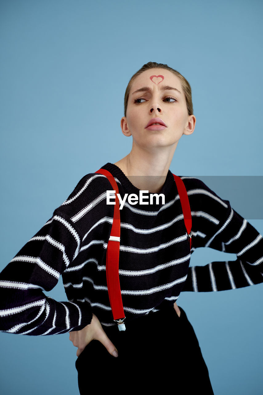 LOW ANGLE VIEW OF YOUNG WOMAN AGAINST BLUE BACKGROUND