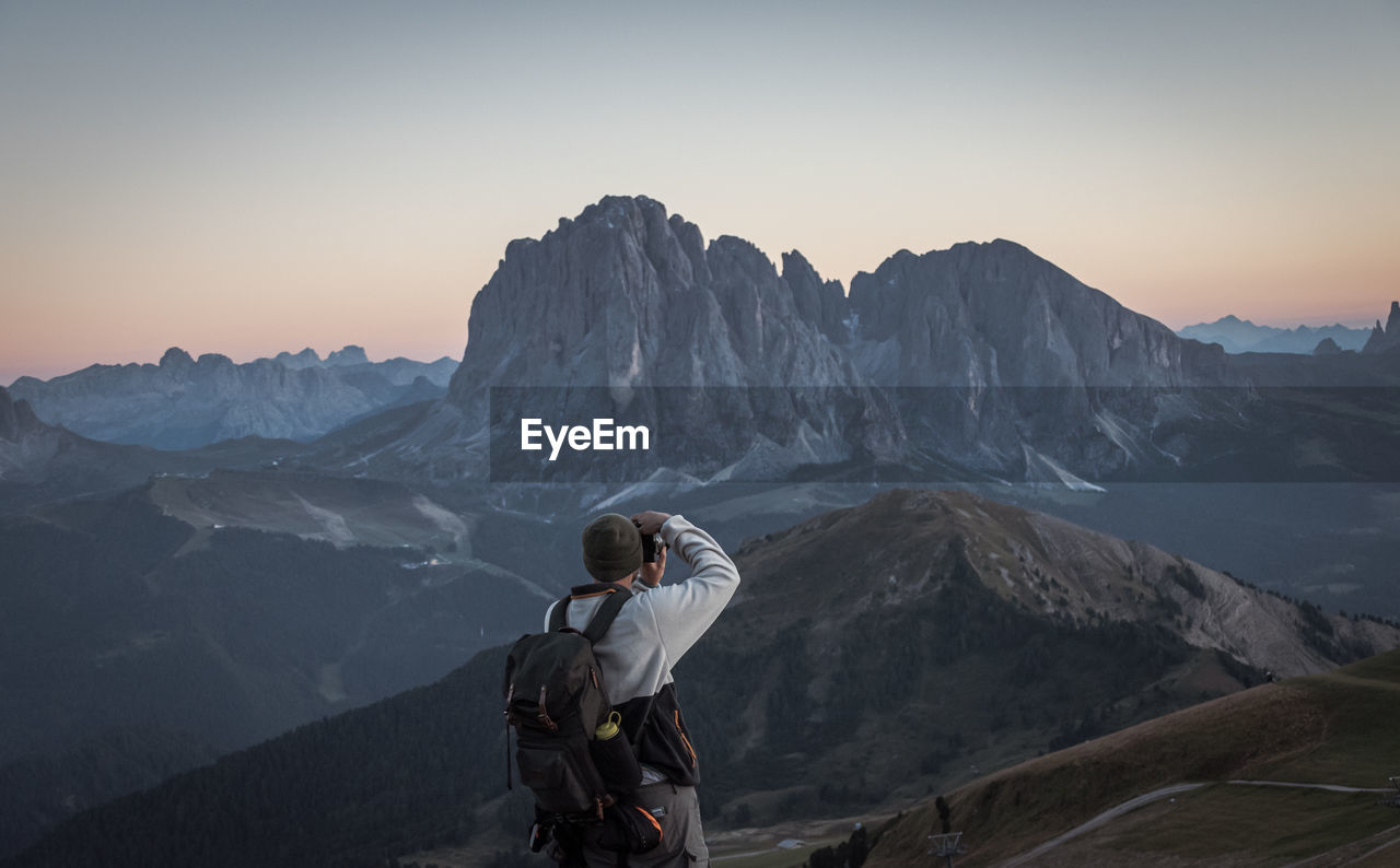 Man photographing on snowcapped mountains against sky