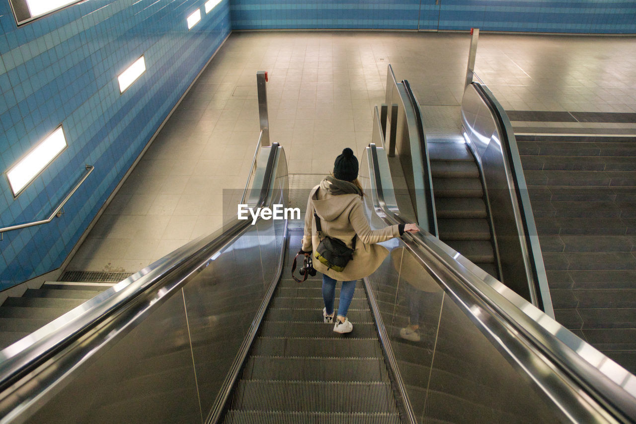 HIGH ANGLE VIEW OF MAN WALKING ON ESCALATOR