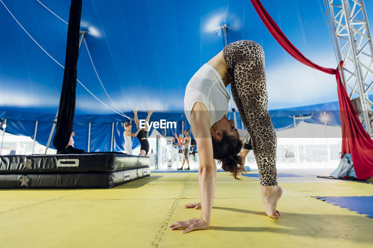 Female artist bending forward while standing on tiptoe at circus