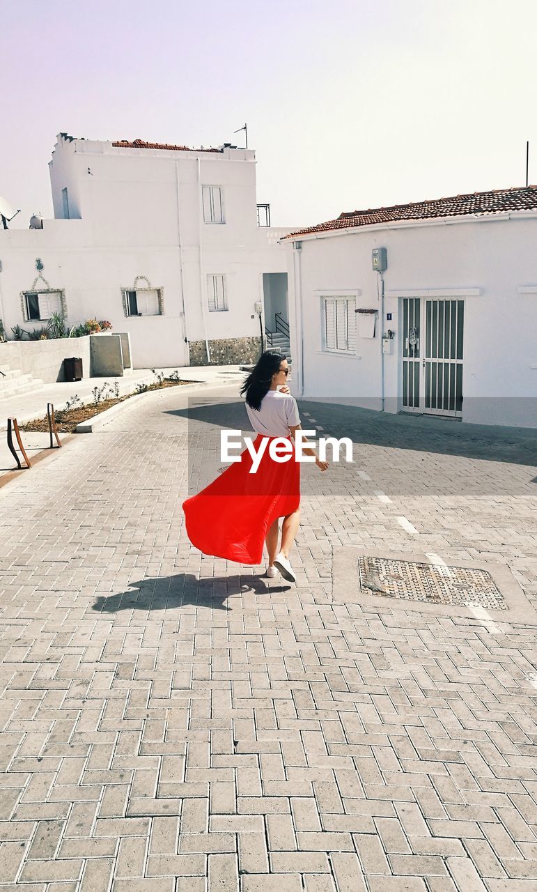 Rear view of woman walking on footpath in city