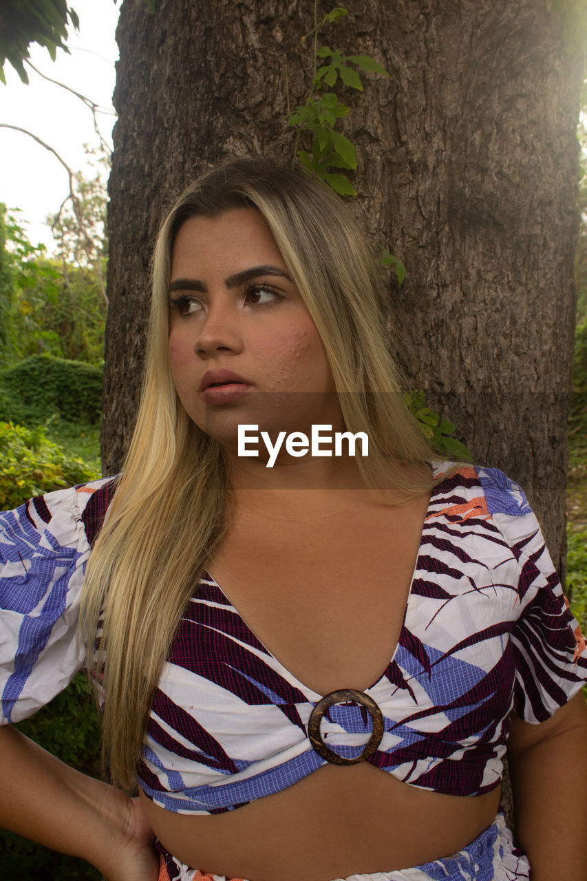 PORTRAIT OF YOUNG WOMAN AGAINST TREE