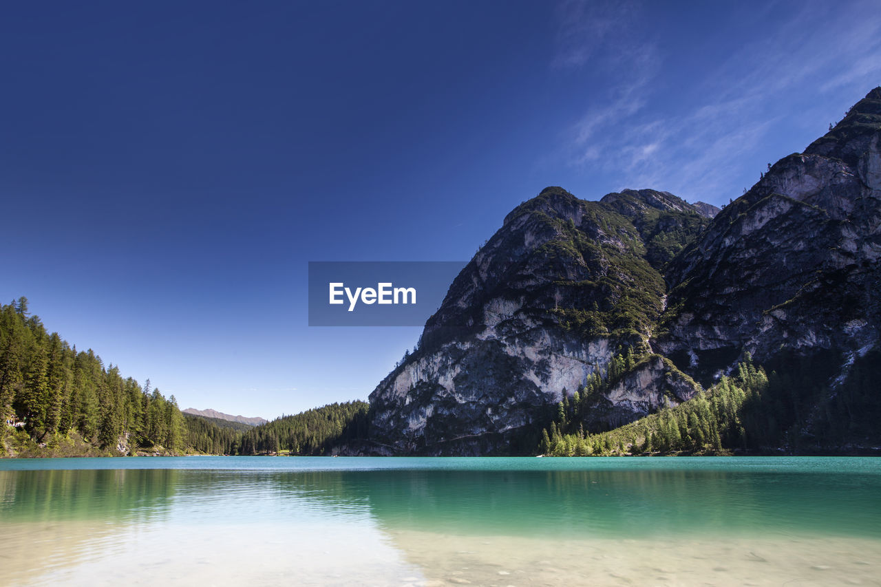 Scenic view of lake and mountains against clear blue sky