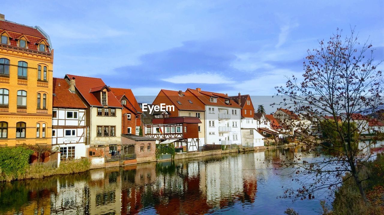 Buildings by river against sky