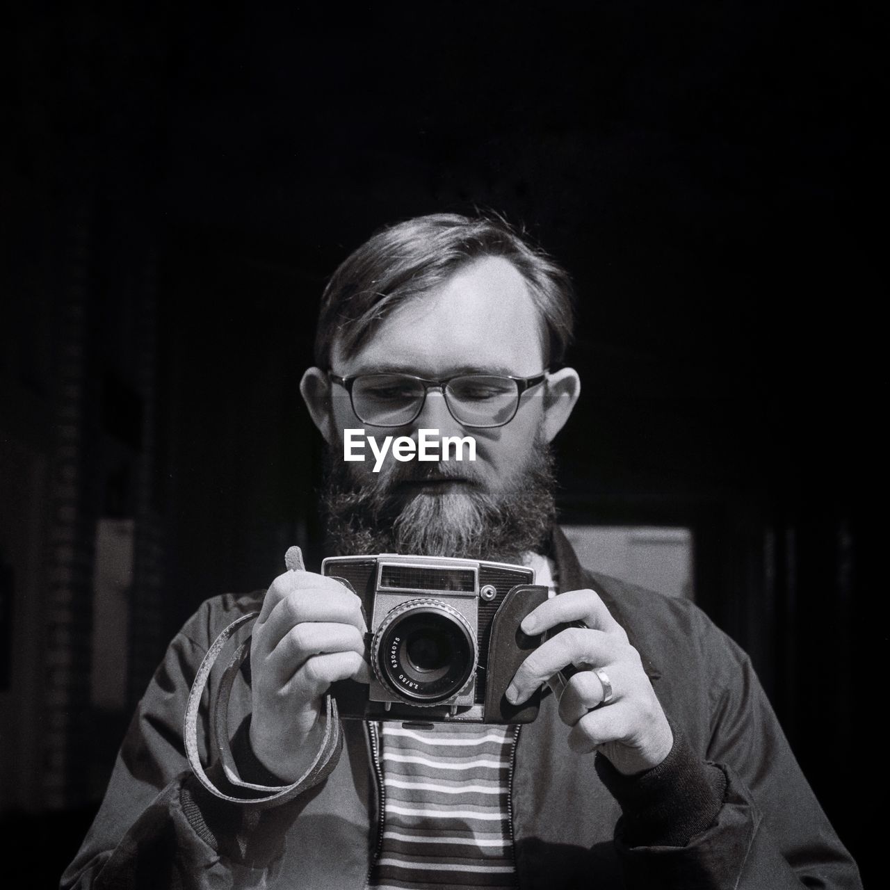 Mid adult man holding camera while standing outdoors