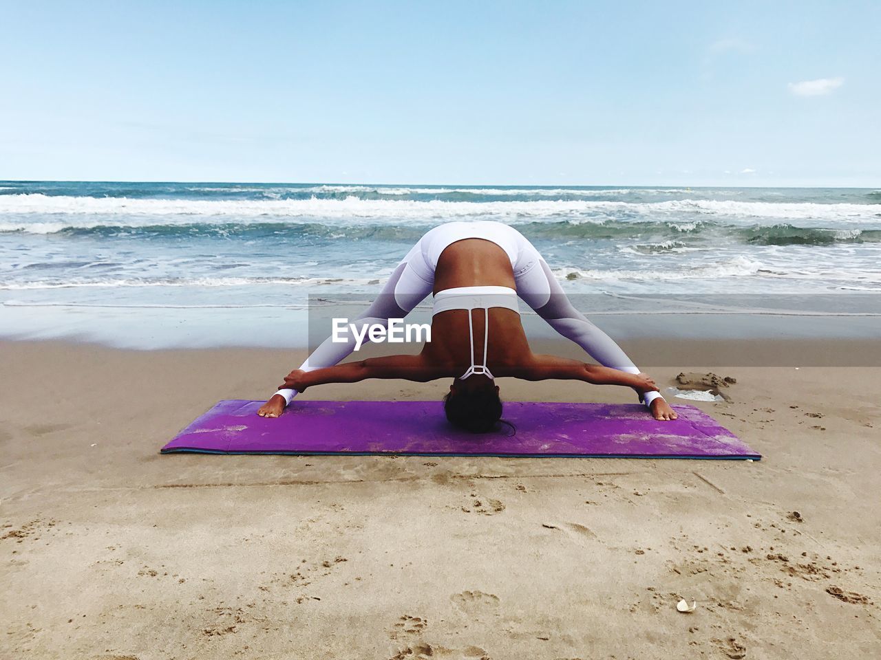 Woman doing yoga at beach against sky