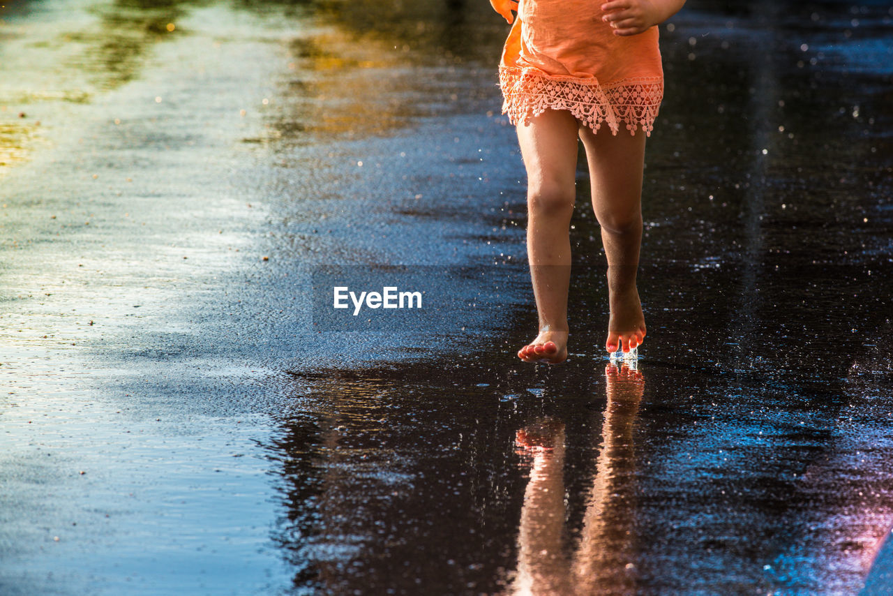 Low section of girl on wet street during rainy season