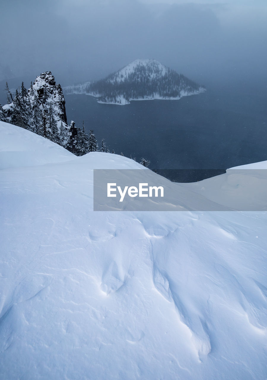 Scenic view of snowcapped mountains by lake against cloudy sky