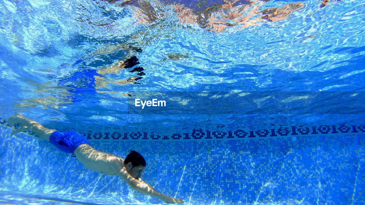 Underwater view of man diving into swimming pool