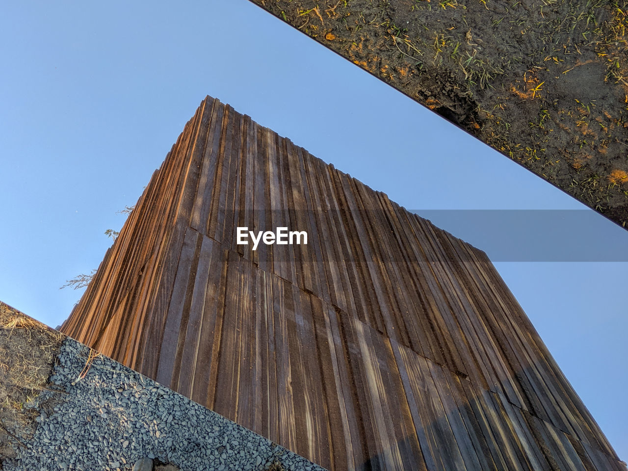 Wooden structure seen against blue sky in a mirror on the ground