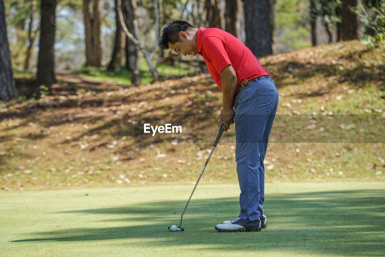 SIDE VIEW OF PERSON STANDING ON GOLF