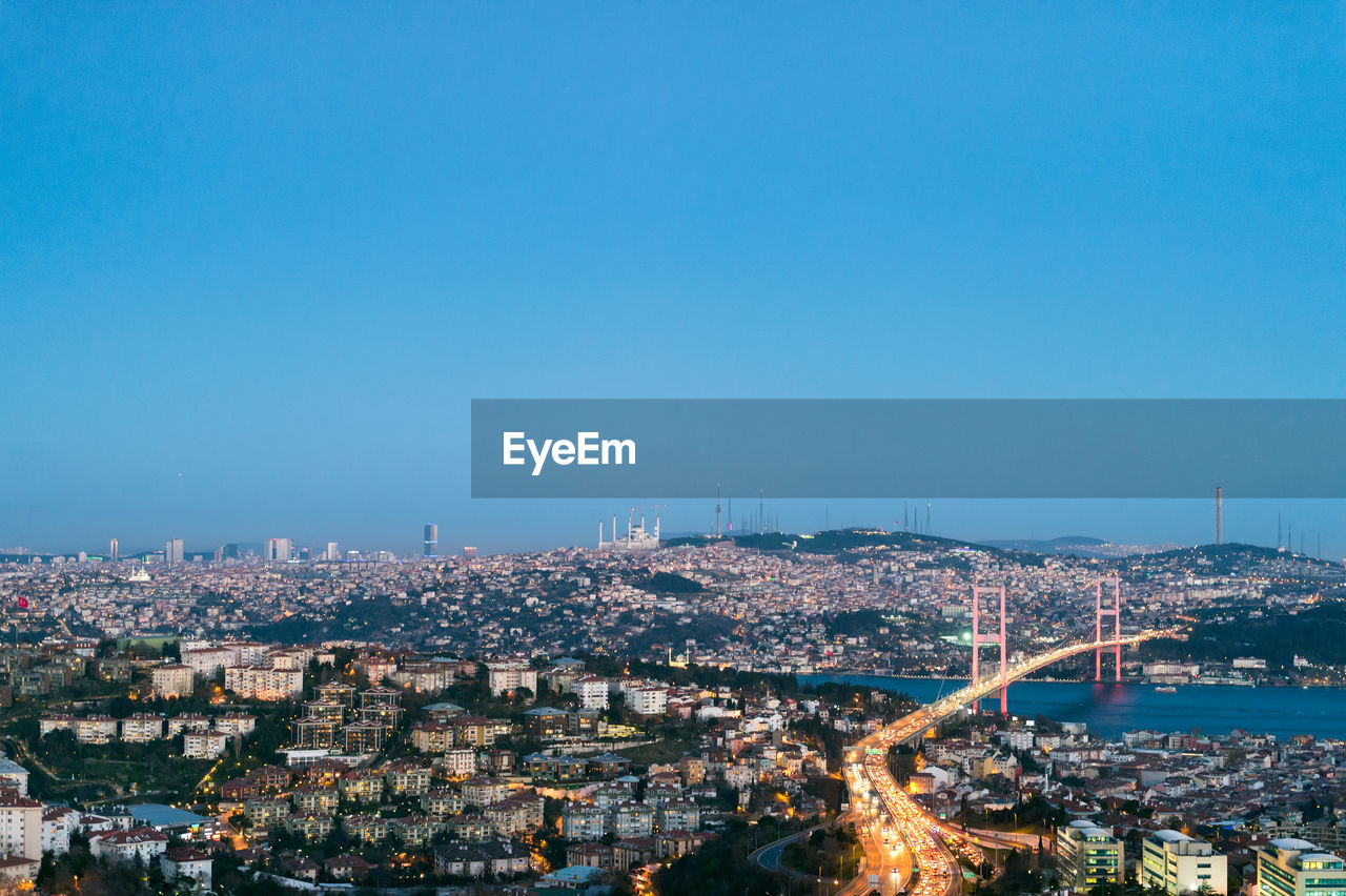 Illuminated cityscape against clear blue sky