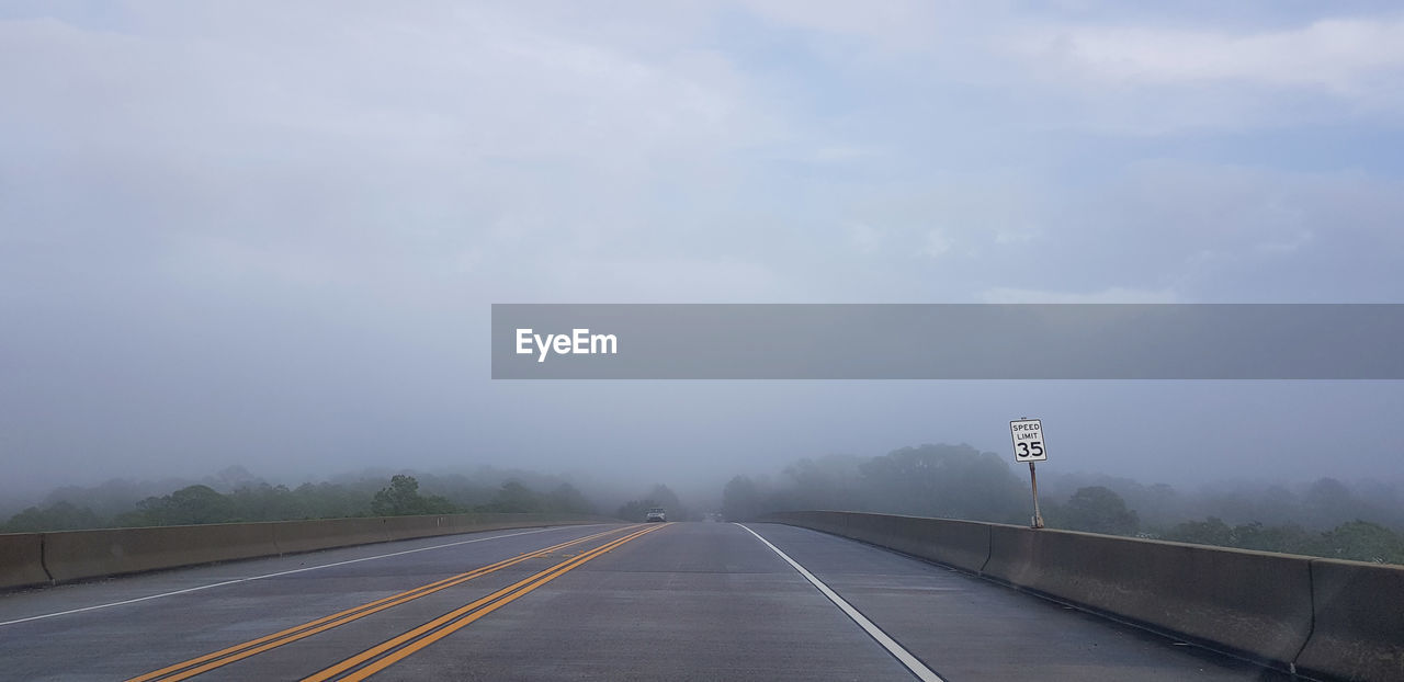 Empty road against foggy sky