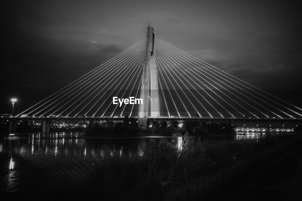 BRIDGE OVER RIVER AGAINST SKY DURING NIGHT