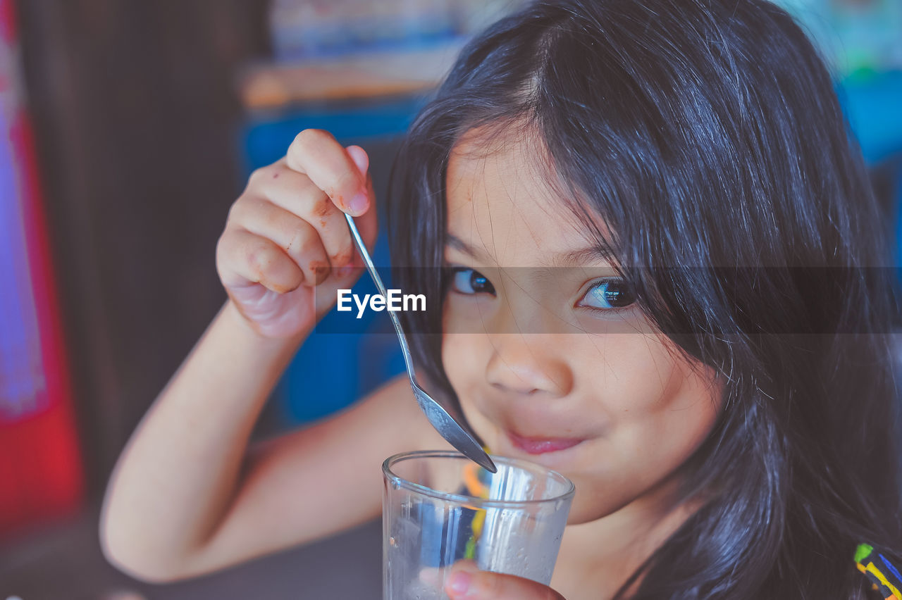 Close-up portrait of girl drinking juice while sitting in restaurant