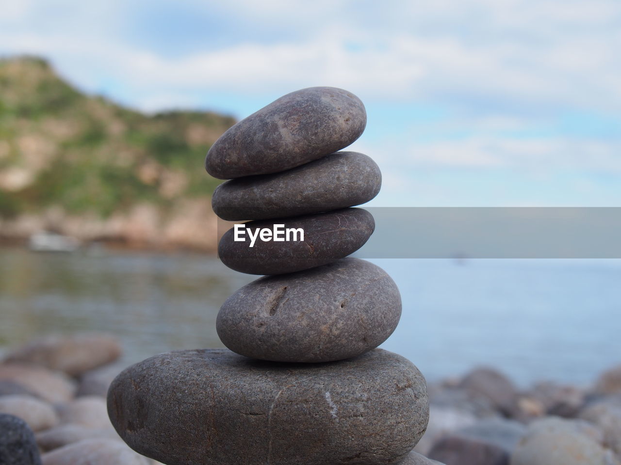 Stack of stones in sea against sky