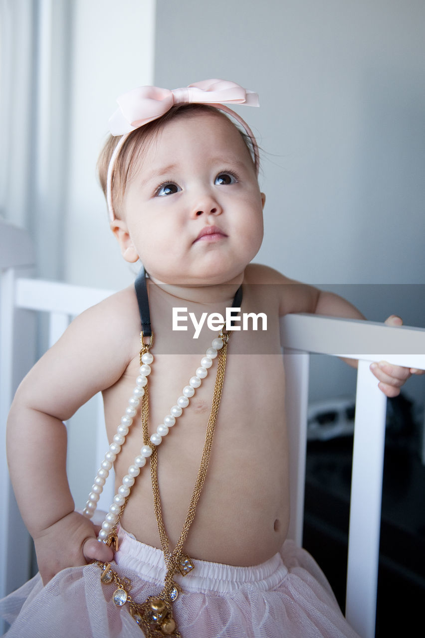 Close-up of cute shirtless baby girl wearing jewelries and headband