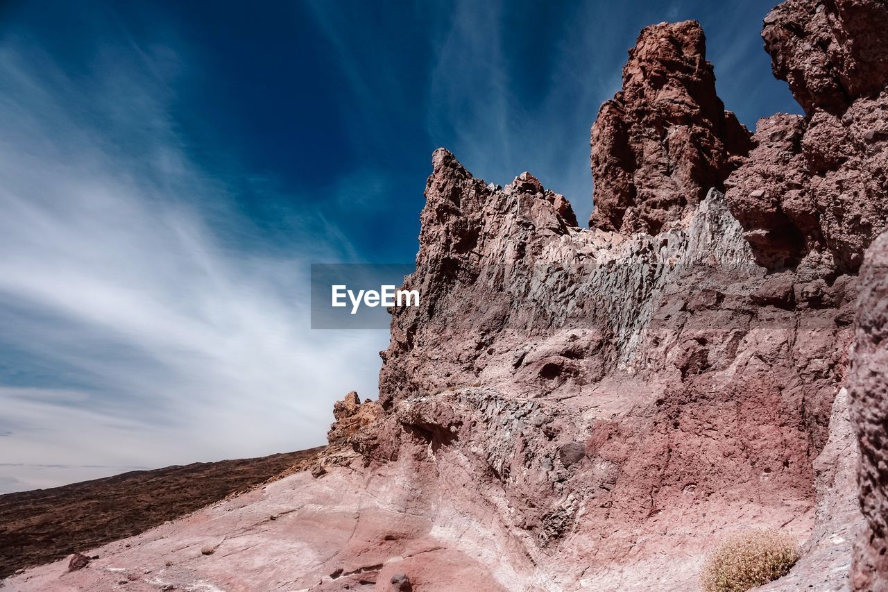 LOW ANGLE VIEW OF ROCKS ON MOUNTAIN AGAINST SKY