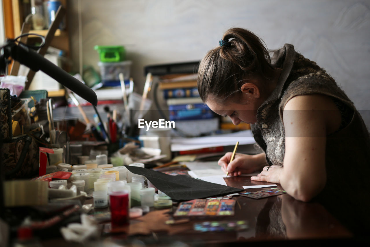 Drawing a sketch on a plate of copper with a metal pen, close-up, materials in a home creative 