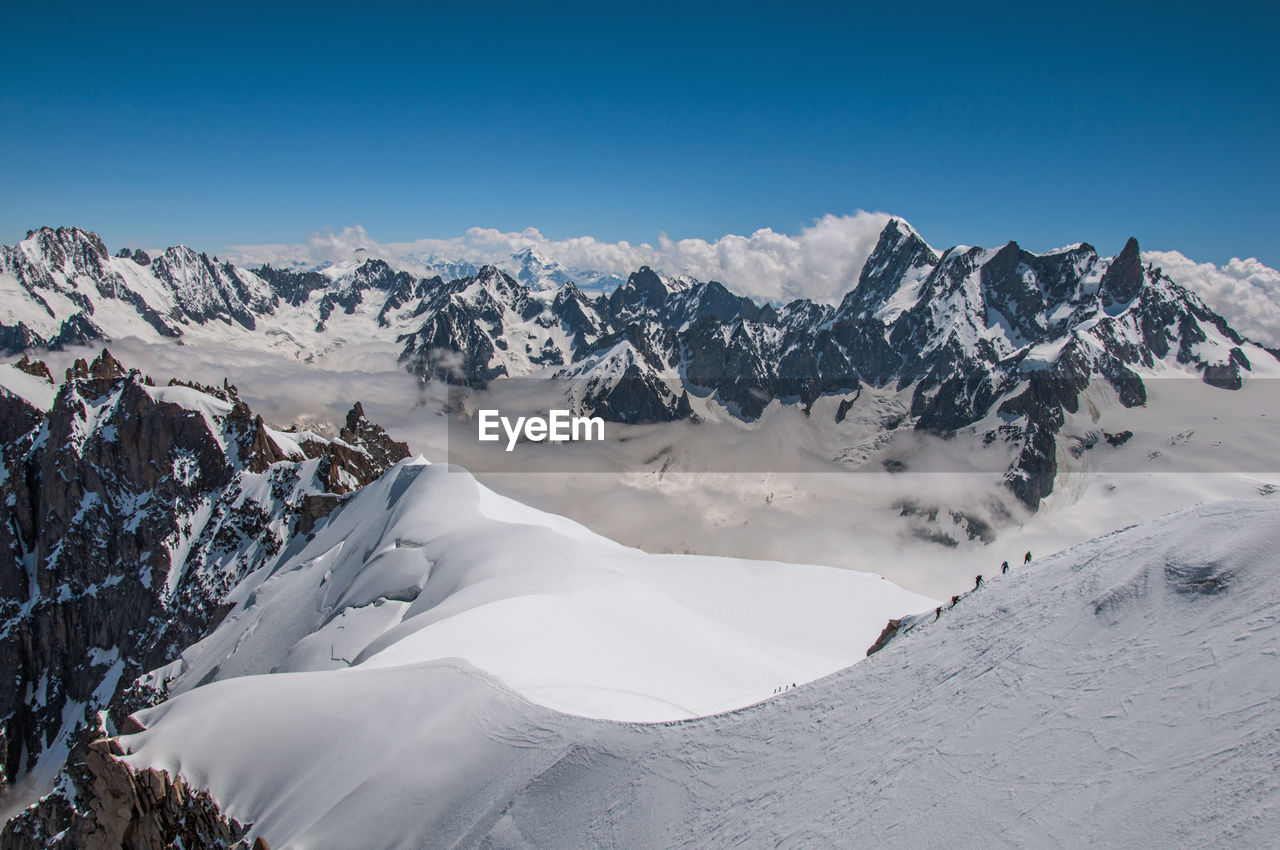 Snowy peaks and mountaineers in a sunny day at the aiguille du midi, near chamonix, france.